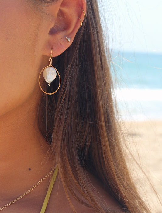 holding pearl earrings